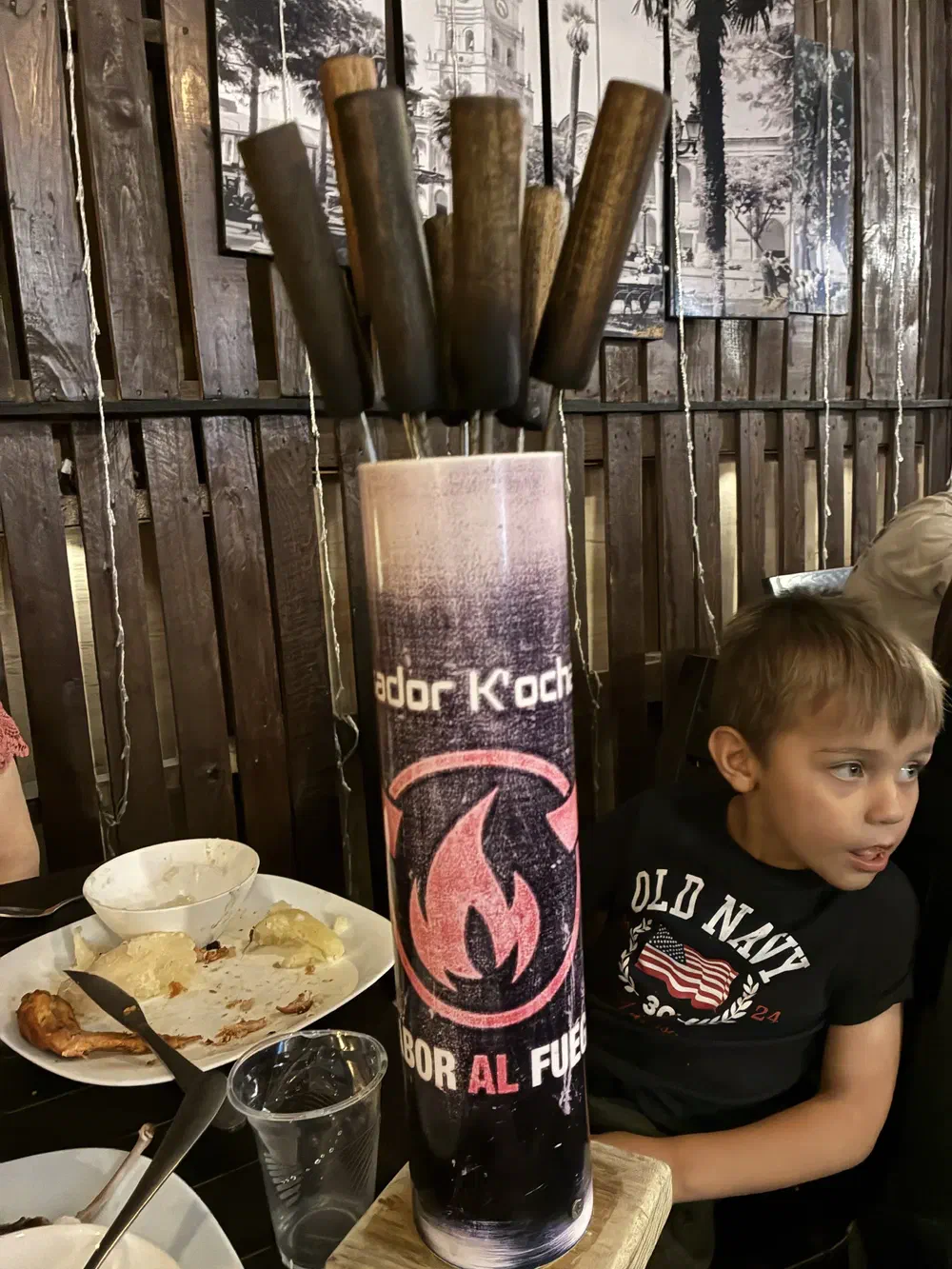 A metal canister of used wooden skewers standing on a restaurant table
