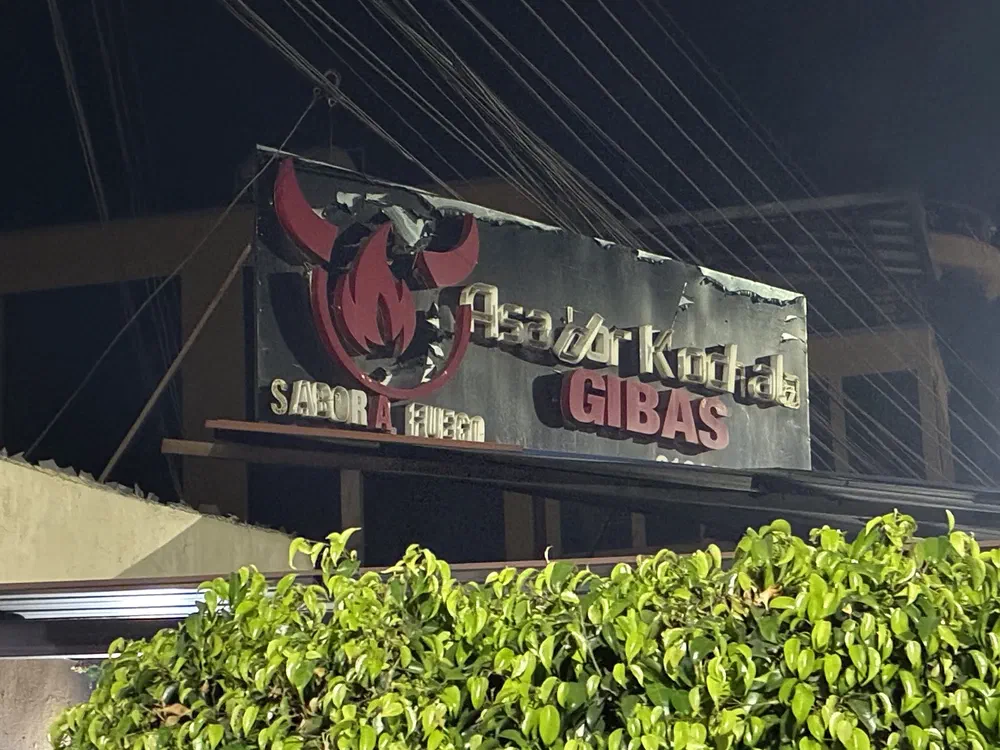 The lit sign for Asador Kochala Gibas at night, reading "Sabor a Fuego"