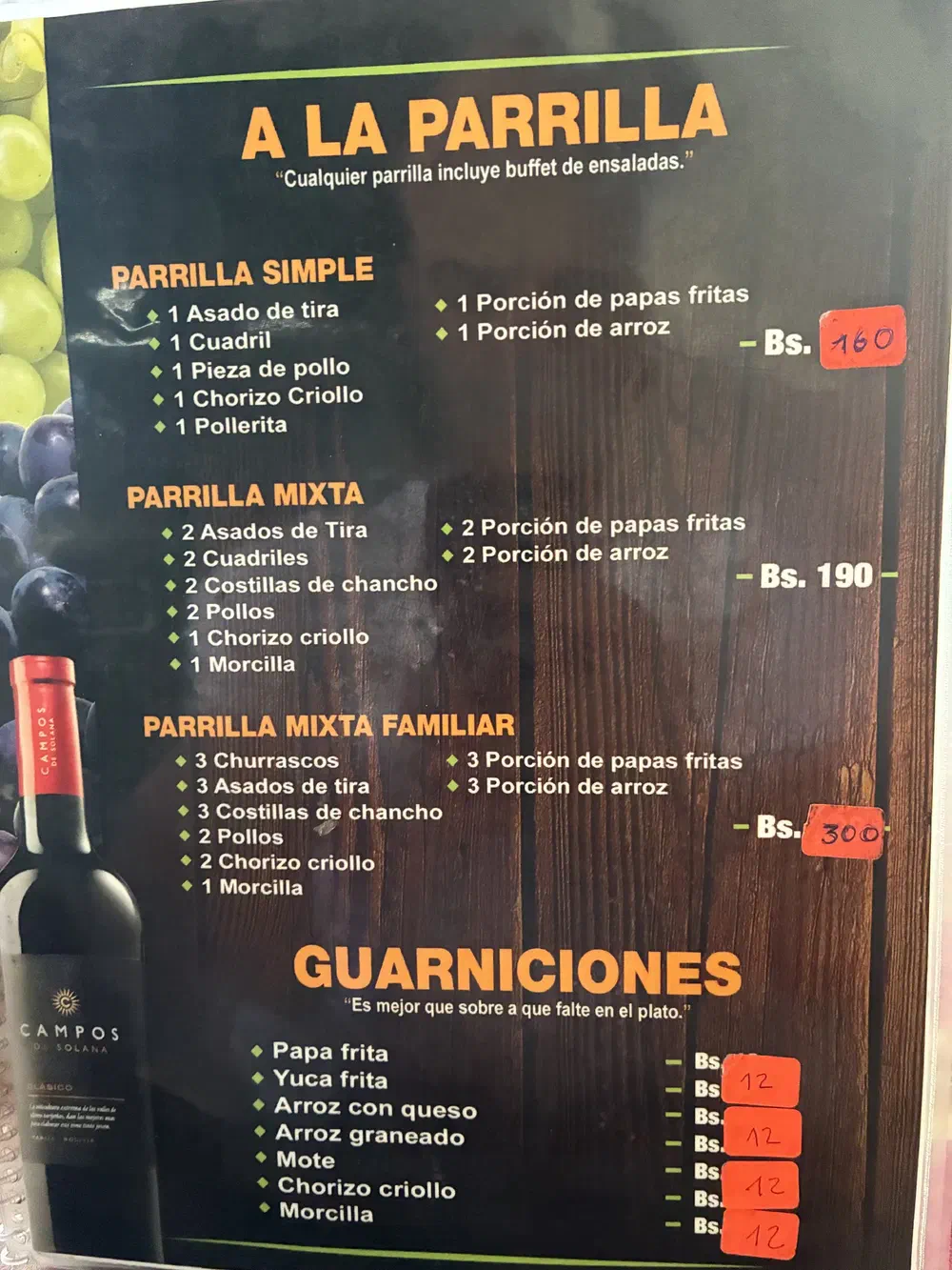 Menu page headed A la Parrilla, listing mixed grills and side dishes